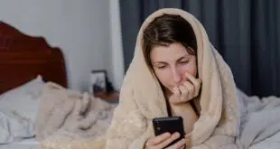 Beautiful young woman on bed at night in underwear reading text message