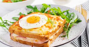 Croque madame sandwich and a cup of latte macchiato coffee on the table.