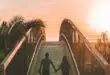 man and woman holding hand while walking on bridge