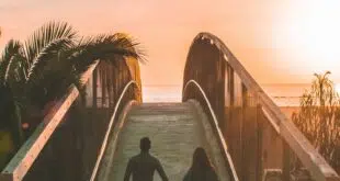 man and woman holding hand while walking on bridge