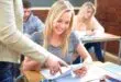 Smiling female student with digital tablet and teacher in classroom