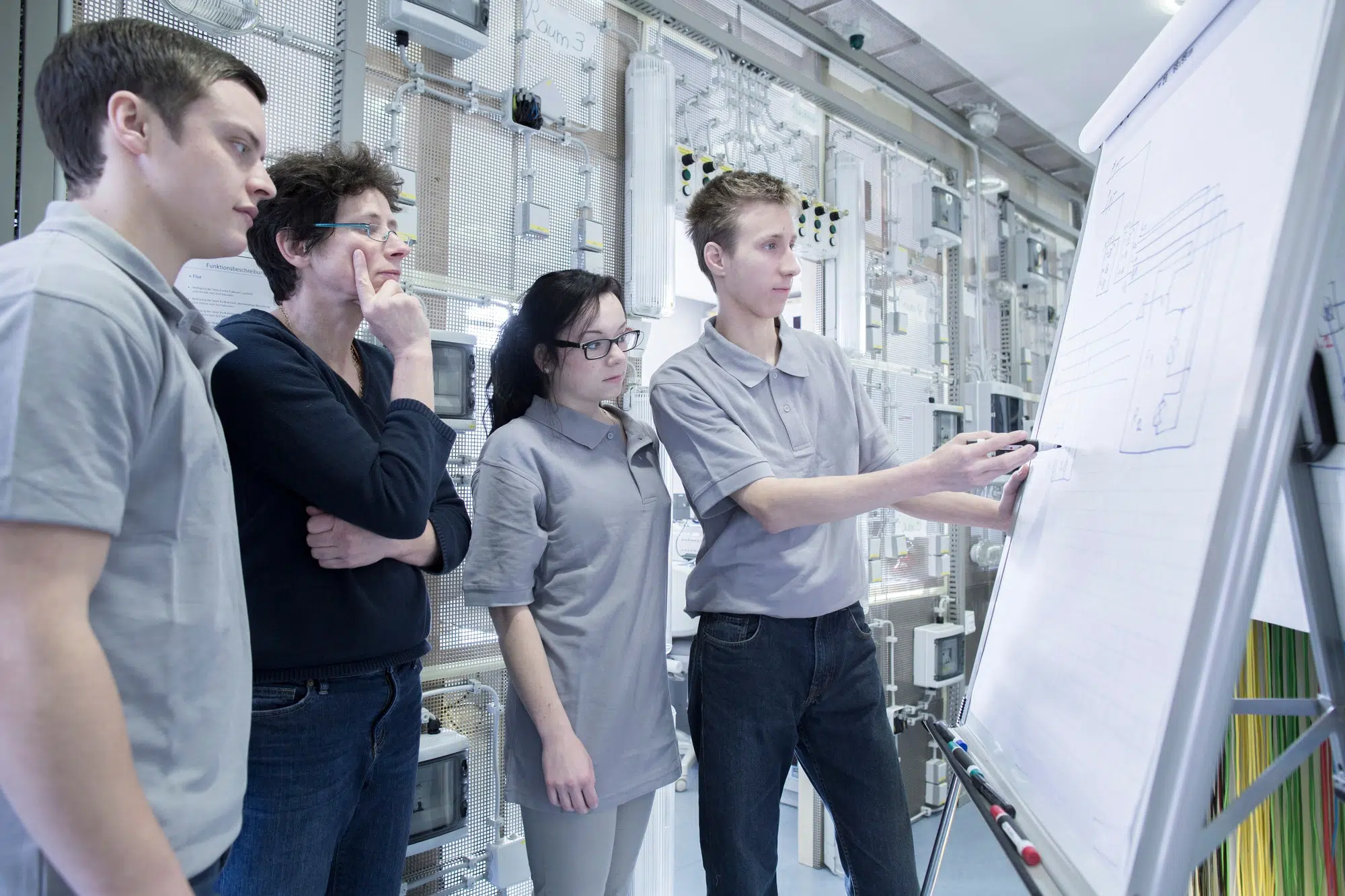Students and teacher at electronics vocational school using flip chart