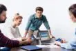 Young businesspeople using digital devices with facebook logo icons on screens