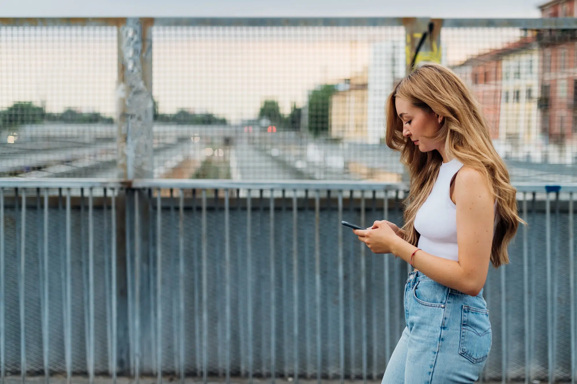 Young caucasian woman walking outdoor using smartphone texting messages